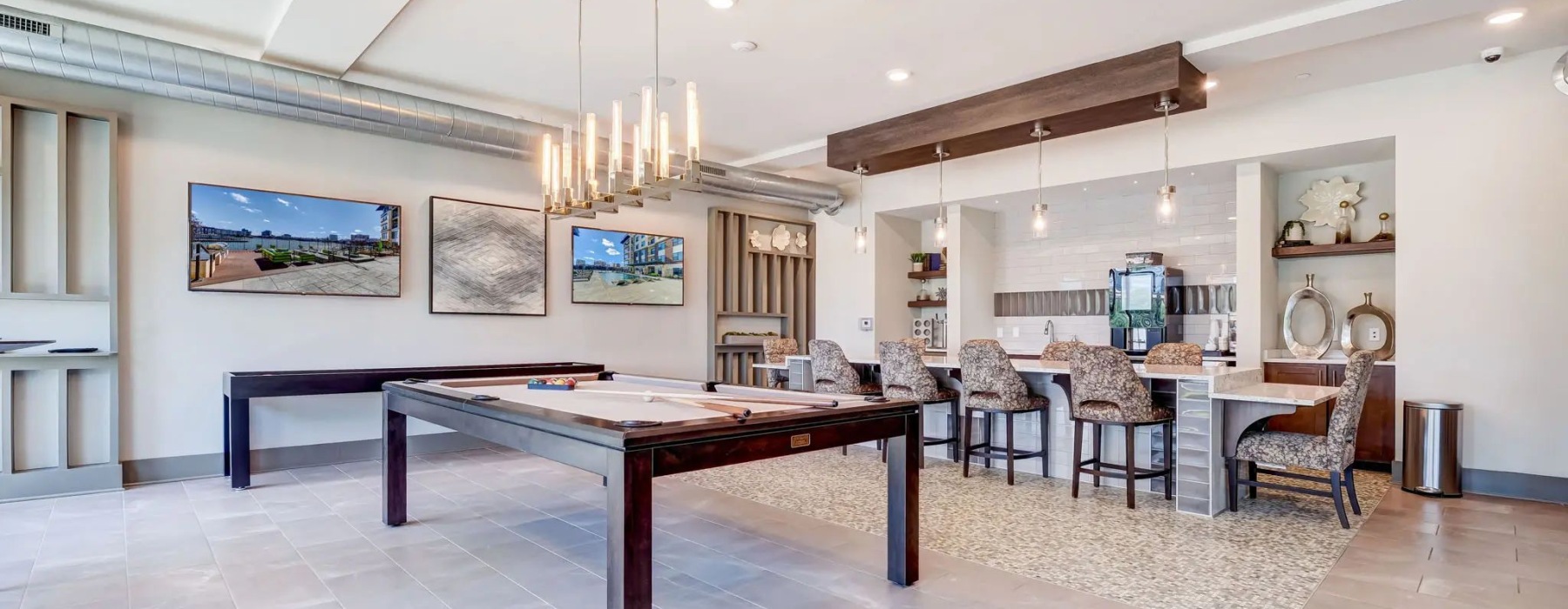 Resident clubroom with billiards table, bar seating, and modern lounge area at The Carolyn apartments